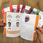 Open book with medical illustrations held by a person on a wooden surface