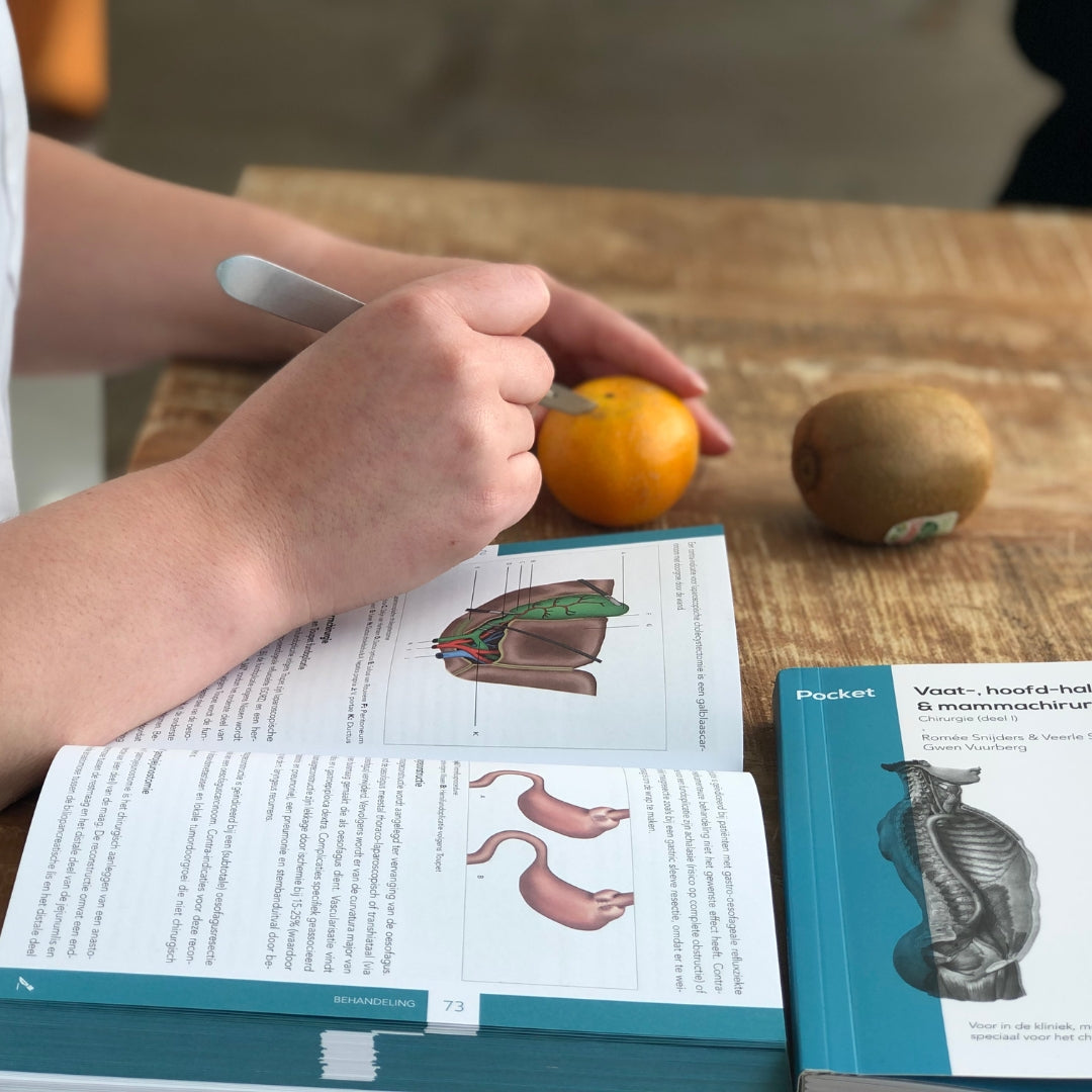 Medical student practicing surgical skills using the Compendium Geneeskunde pocket books
